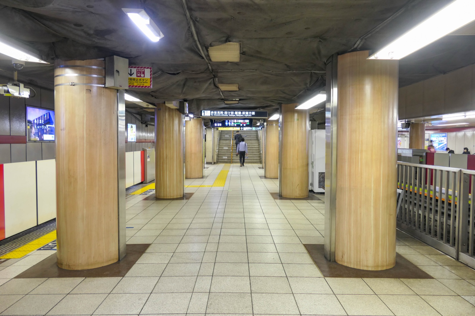 The platform of Kasumigaseki Station on the Tokyo Metro, photographed in daylight — clean tiled platform, illuminated panel signage, a stationary train at the platform edge.