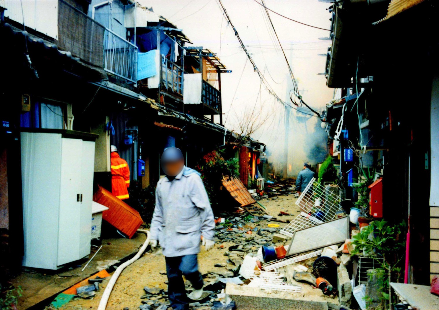 Damage from the 1995 Great Hanshin earthquake in Kobe, Japan, showing collapsed and damaged buildings along a street.