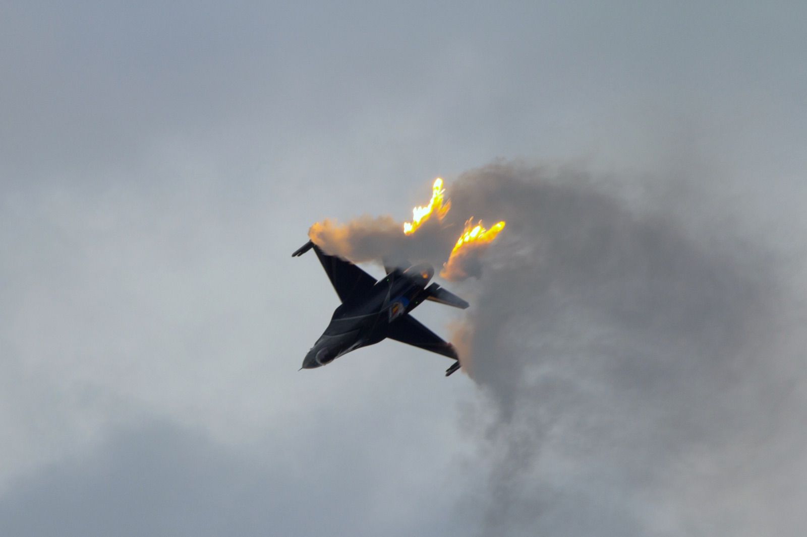 A General Dynamics F-16 fighter releasing bright defensive flares against a dark sky.