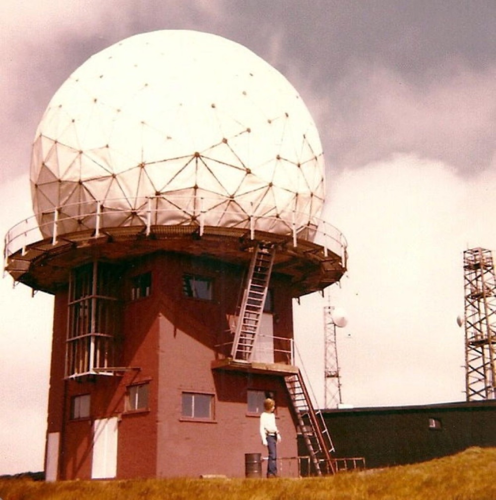 A civilian air-traffic-control radar installation with a rotating antenna on a hilltop.