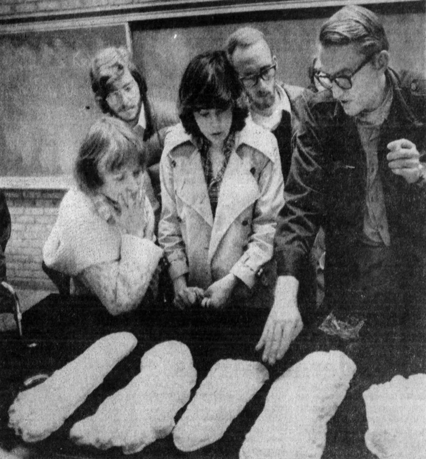 The anthropologist Grover Krantz holding up two large plaster casts of alleged Bigfoot footprints, one in each hand, indoors.