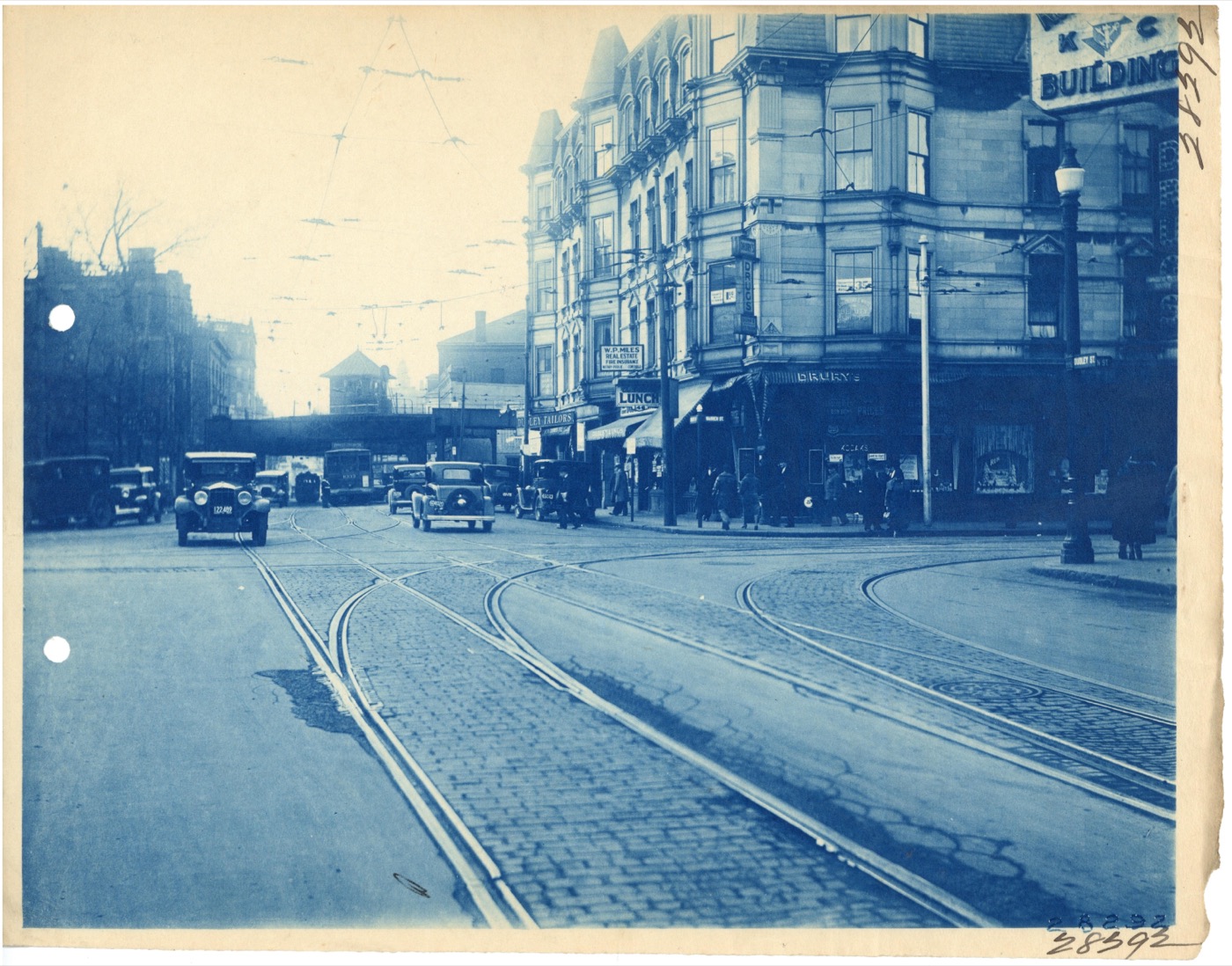 A Boston street scene from the 1920s, with period buildings, shopfronts, and streetcar tracks.