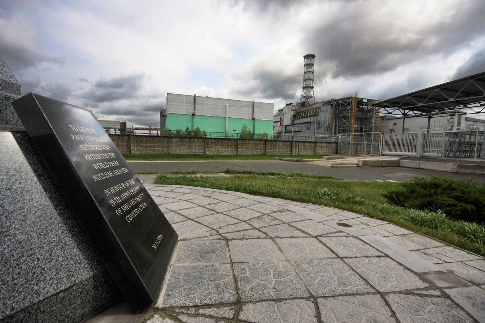 The damaged Chernobyl reactor 4 building, encased in the first sarcophagus, photographed in 2009 with the memorial in the foreground.