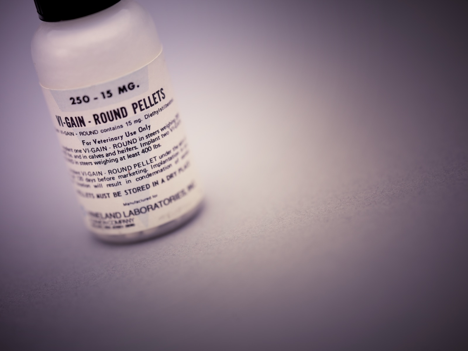 A small bottle labelled 'VI-GAIN Round Pellets, 250 - 15 mg, contains 15 mg Diethylstilbestrol, For Veterinary Use Only,' from Vineland Laboratories, photographed against a pale background.