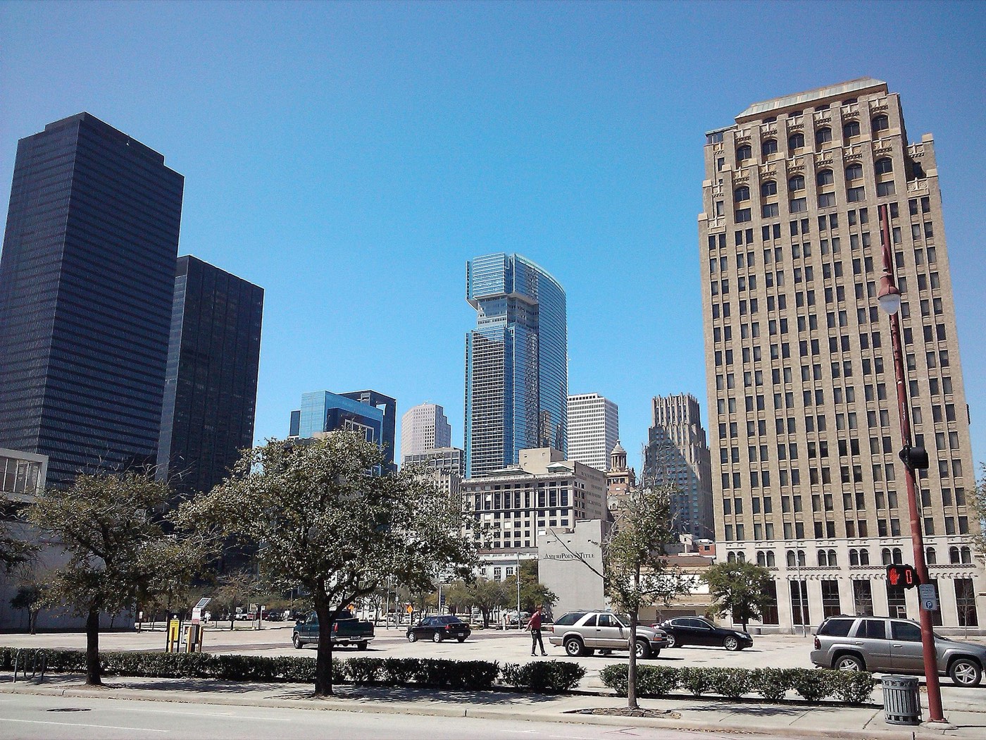 The downtown Houston skyline, a cluster of glass and steel skyscrapers under a blue sky.