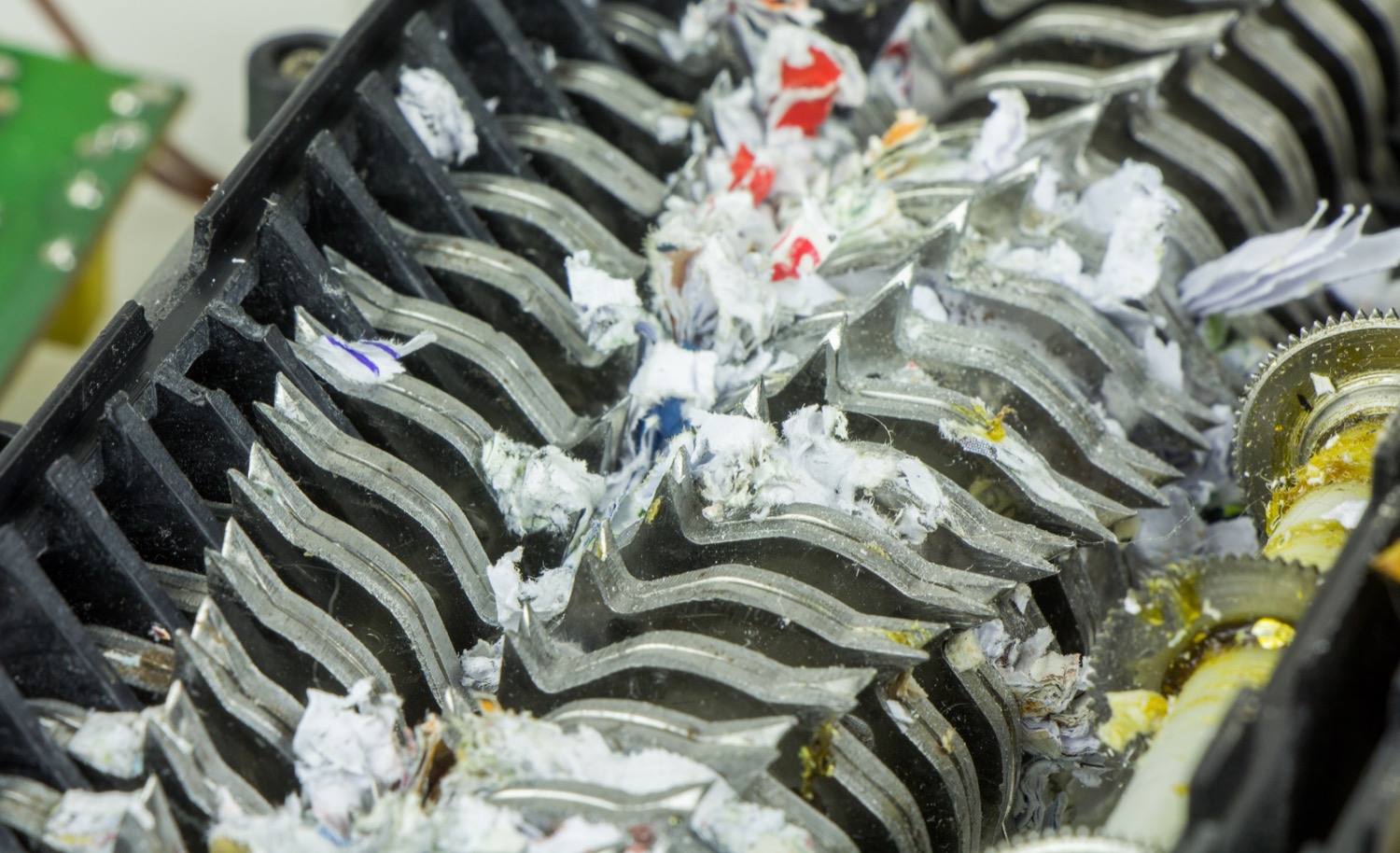 A close-up of a paper shredder with documents being fed into it and shredded into strips.