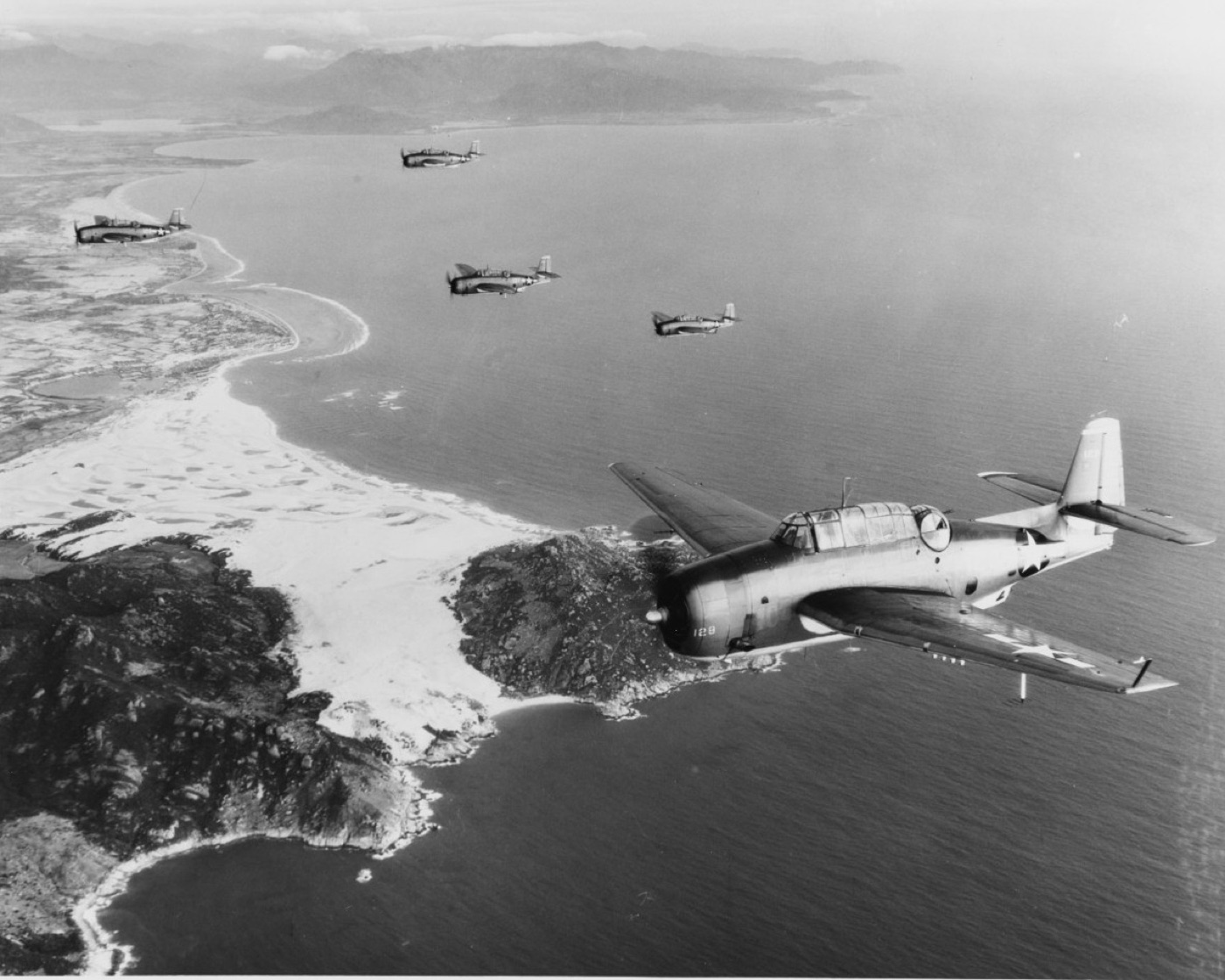 A formation of TBF/TBM Avenger torpedo bombers in flight over the ocean.