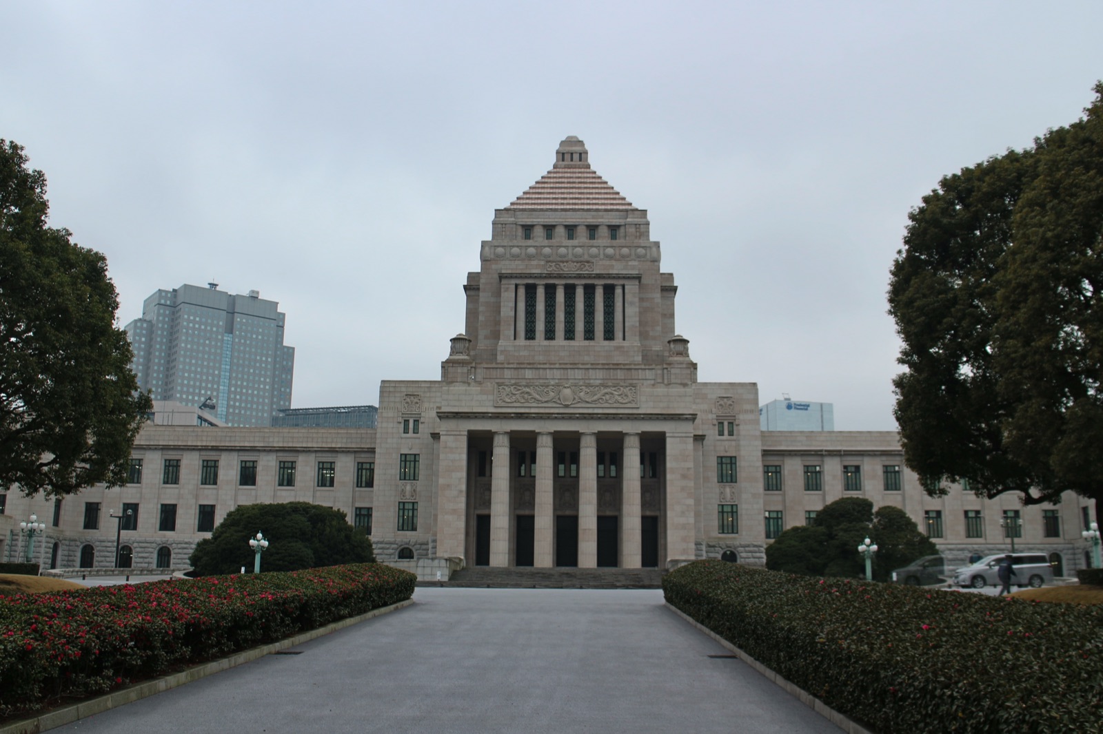 The National Diet Building in Tokyo — a symmetrical 1930s granite parliament building with two wings flanking a central stepped pyramidal tower, photographed from the front under a clear sky.