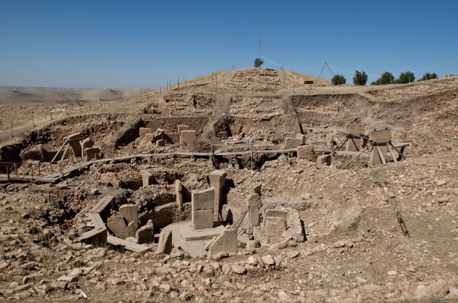 The excavated stone enclosures of Göbekli Tepe, with tall T-shaped limestone pillars standing in circular arrangements.