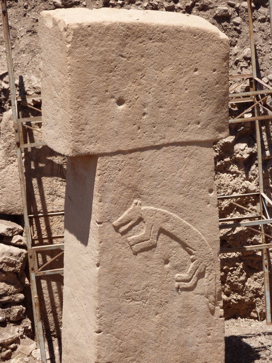 A tall T-shaped limestone pillar at Göbekli Tepe standing against the sky.