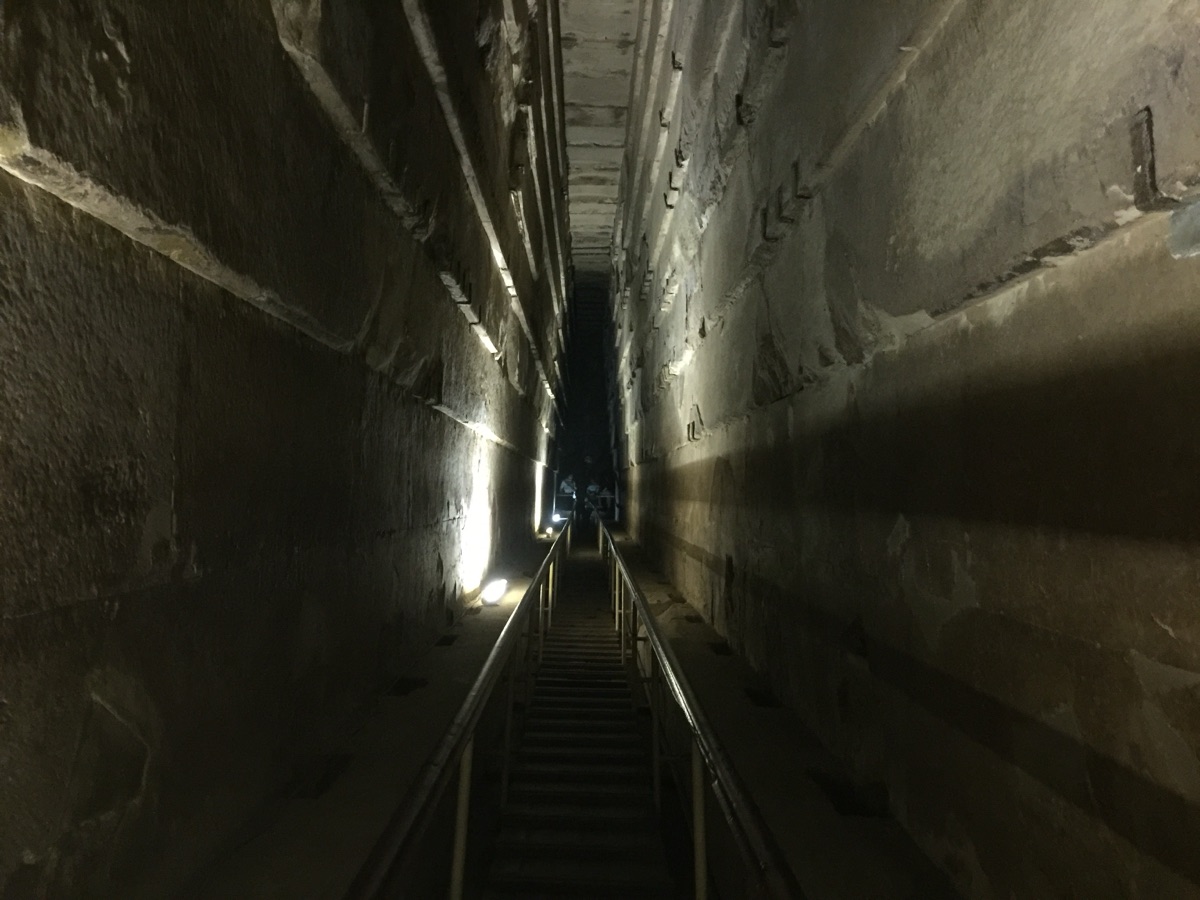The Grand Gallery inside the Great Pyramid, a tall narrow corridor with a corbelled stone ceiling ascending steeply.