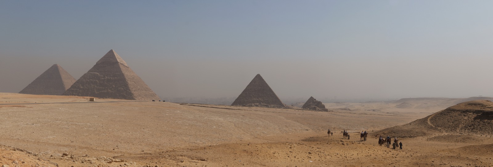 A panoramic view of the three main pyramids of Giza rising from the desert plateau.