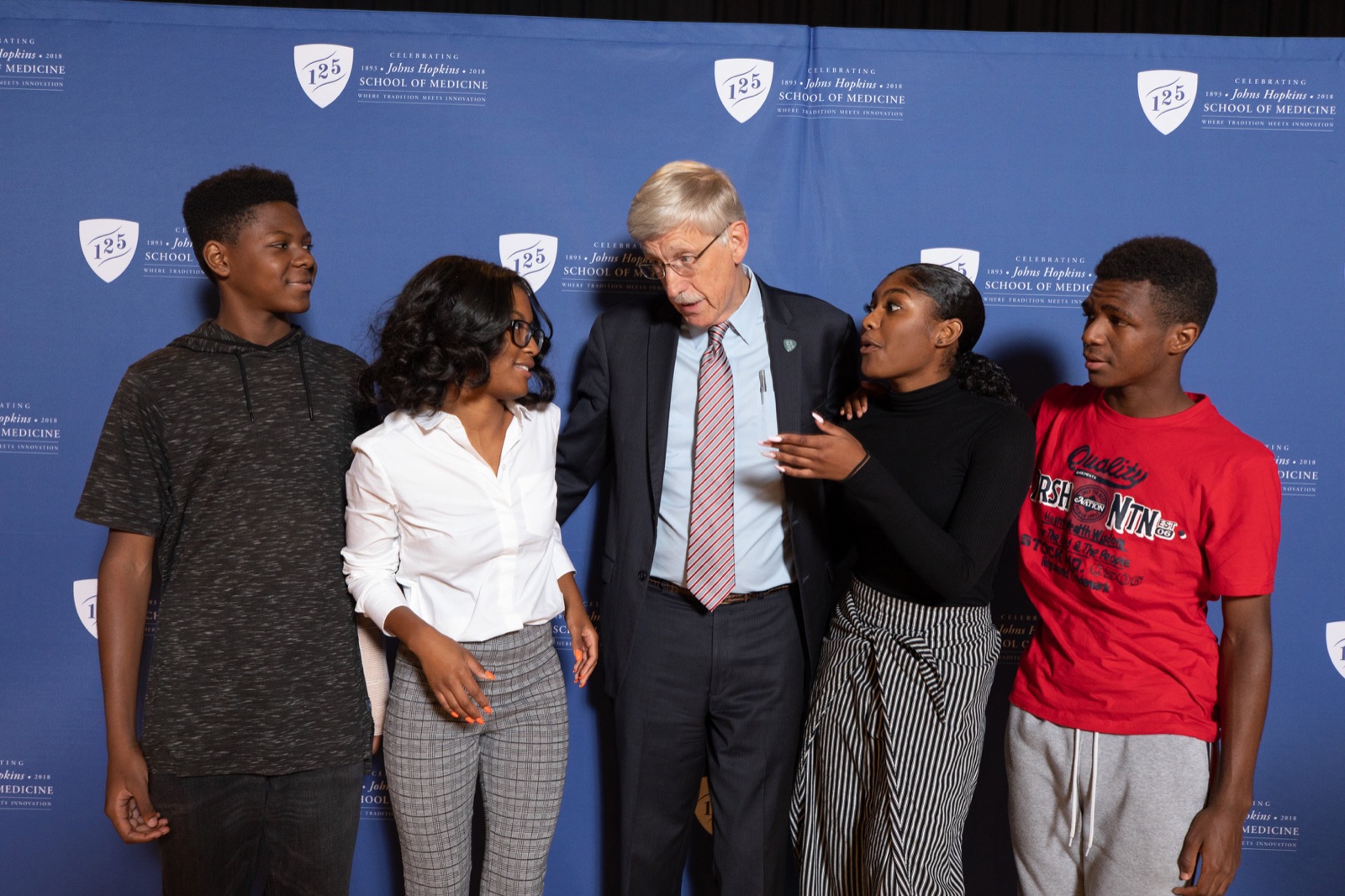 A 2018 photograph of National Institutes of Health director Francis Collins seated and talking with several members of the Henrietta Lacks family in an office.