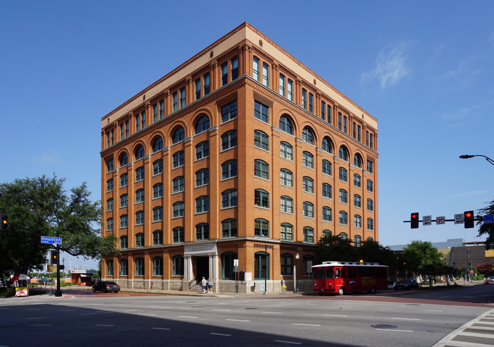 The Texas School Book Depository building in Dallas, photographed in daylight — a six-storey red-brick building of pressed-tin cornice and tall narrow windows.
