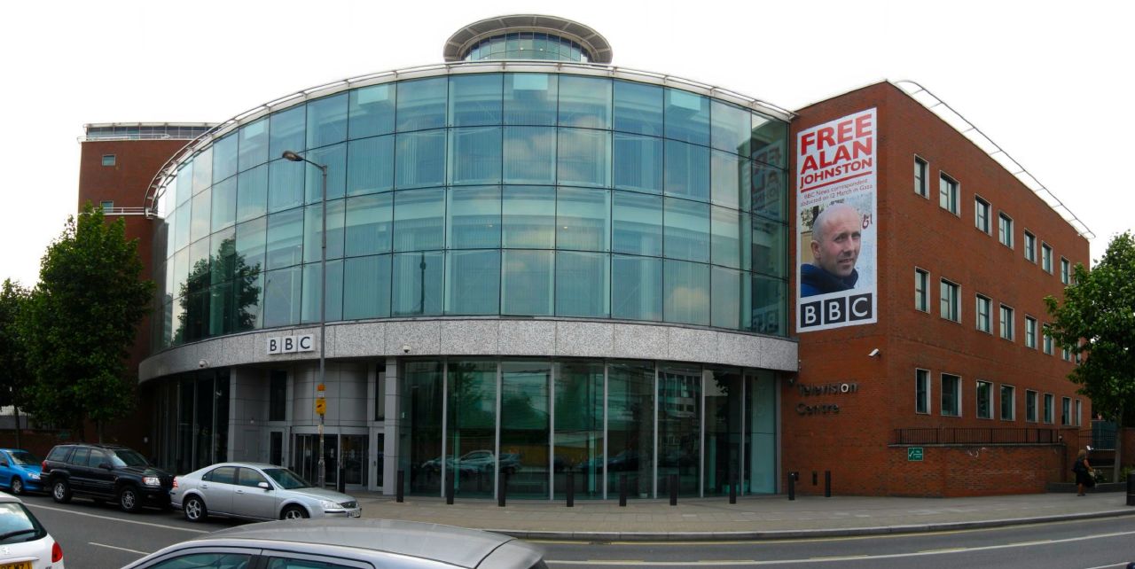 BBC Television Centre, White City, London — a panoramic exterior view of the curved Television Centre building and its central courtyard with the Helios statue, photographed at street level.