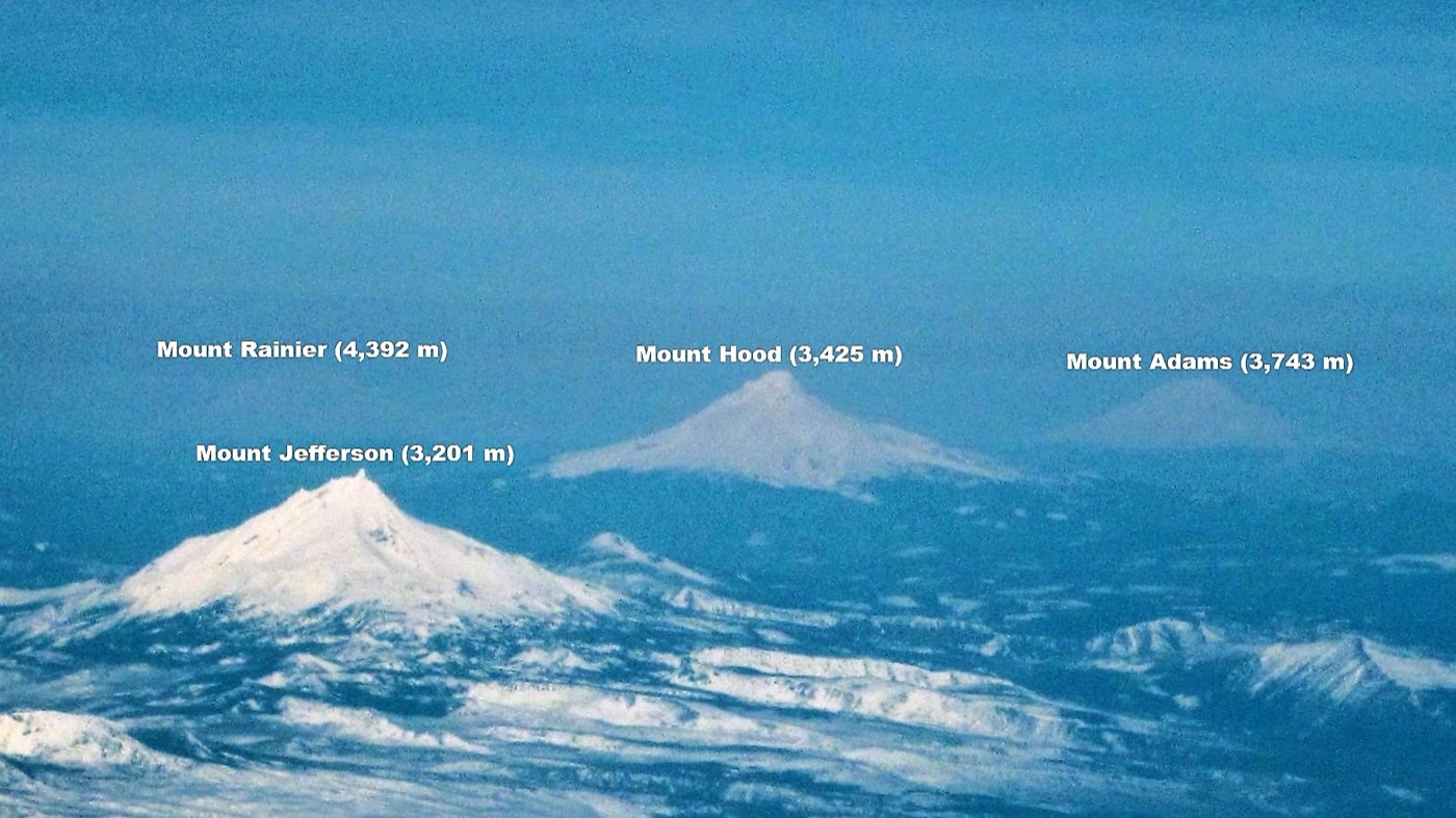An aerial view of the volcanic peaks of the Cascade Range, including Mount Rainier and Mount Adams.