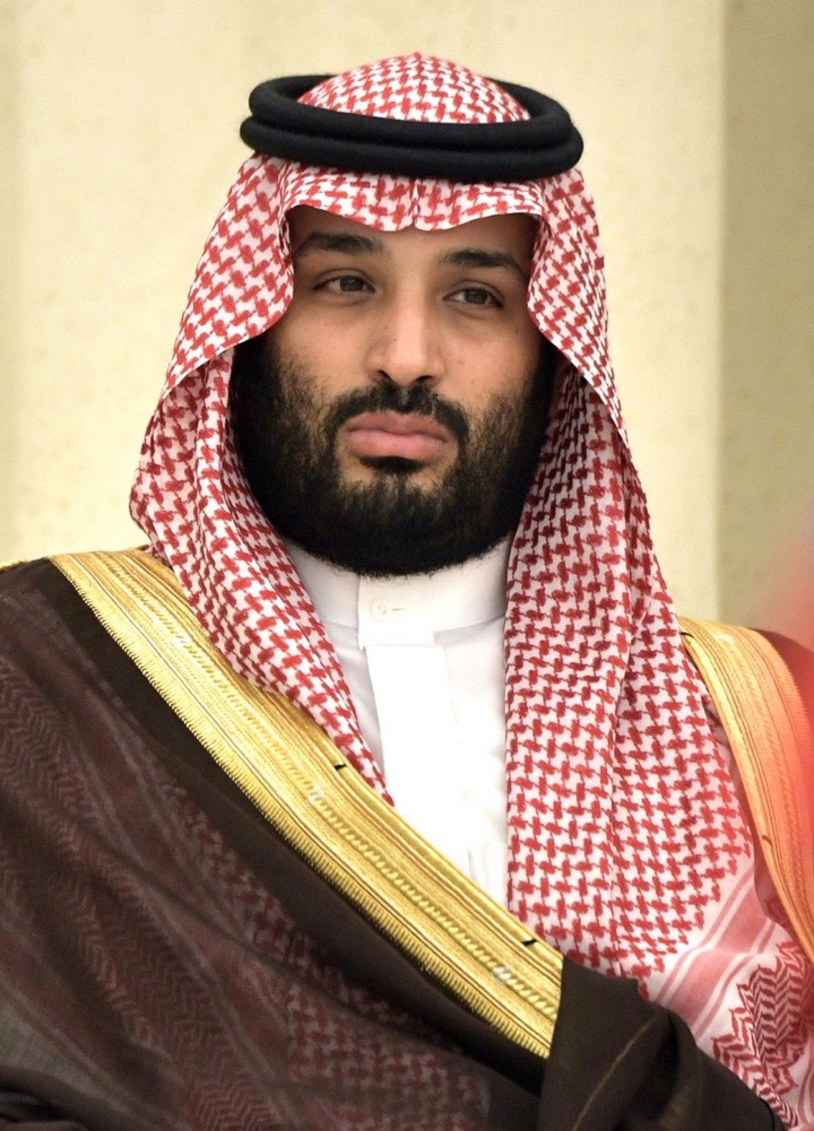 Mohammed bin Salman photographed in October 2019 — wearing traditional Saudi white robes and red-checked head-scarf, looking past the camera.