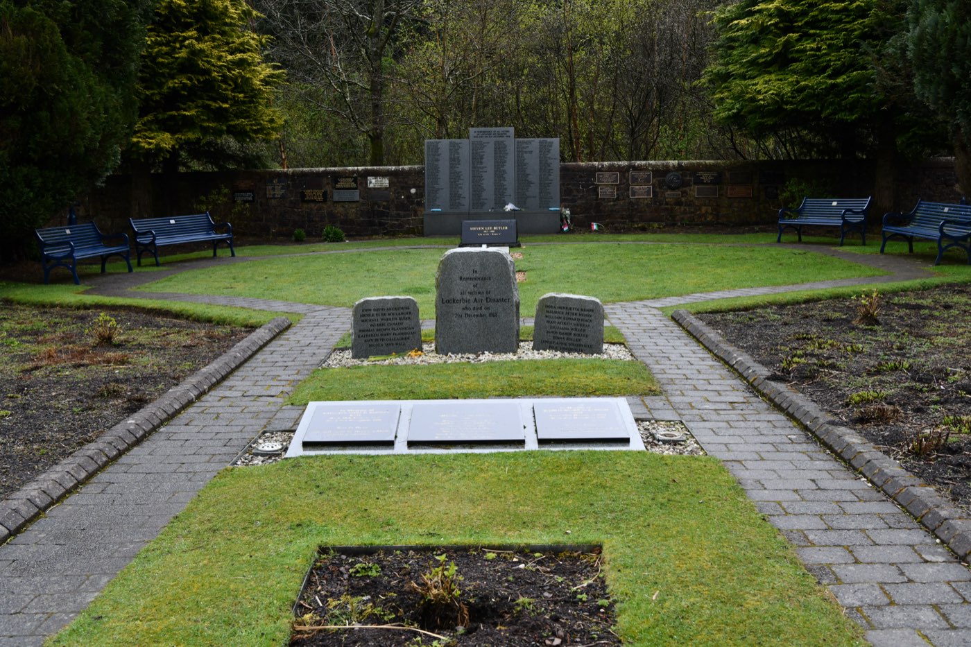 The Lockerbie Air Disaster Memorial Garden at Tundergarth Mains, Dumfries and Galloway, Scotland — a landscaped memorial garden with stone wall, mature trees, and engraved memorial stones in a peaceful rural setting.