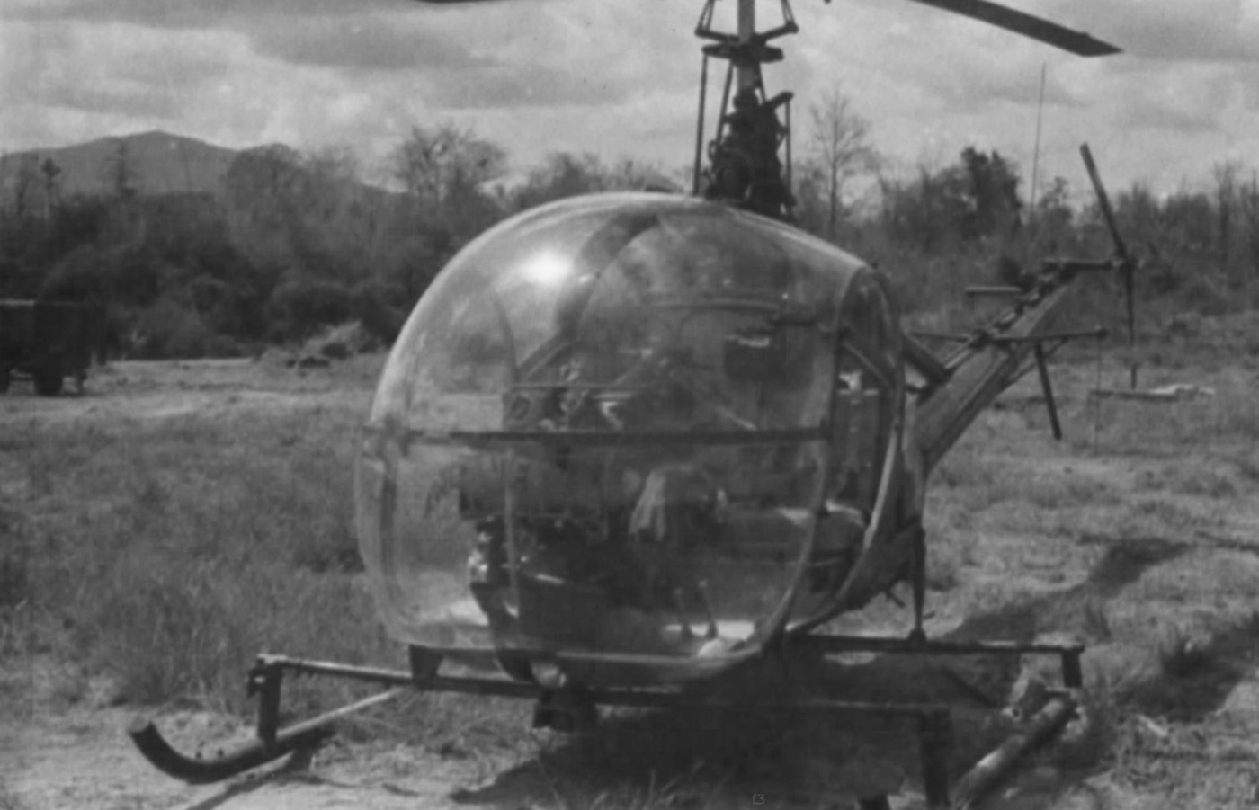 A U.S. Army OH-23 Raven observation helicopter on a Vietnam-era airfield — a small two-seat light helicopter with characteristic bubble canopy and tail boom, preparing for takeoff, ground crew visible.