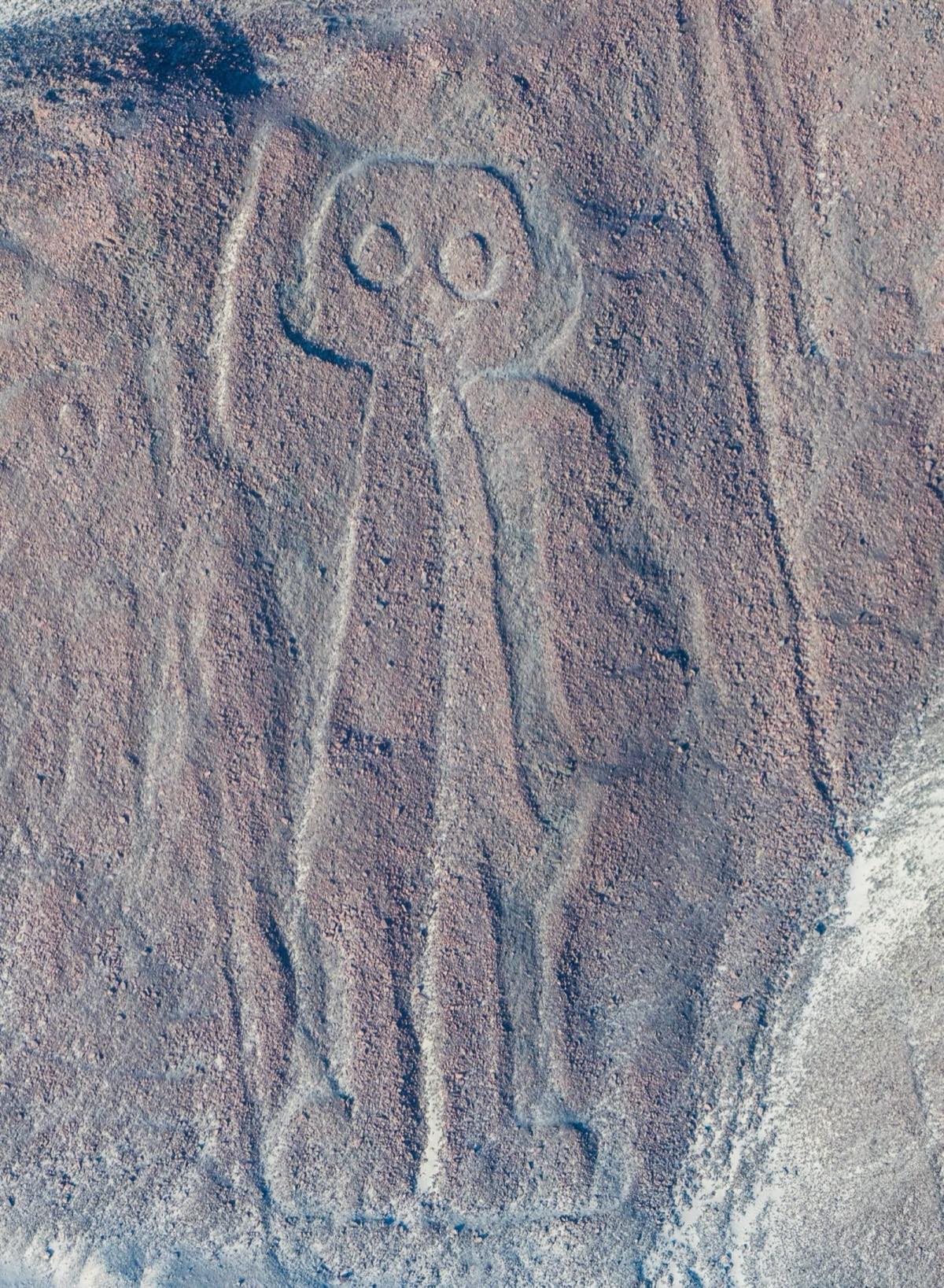 The Nazca geoglyph nicknamed 'the Astronaut' or 'Owlman', a humanoid figure with a rounded head and large round eyes carved into a hillside, one hand raised.