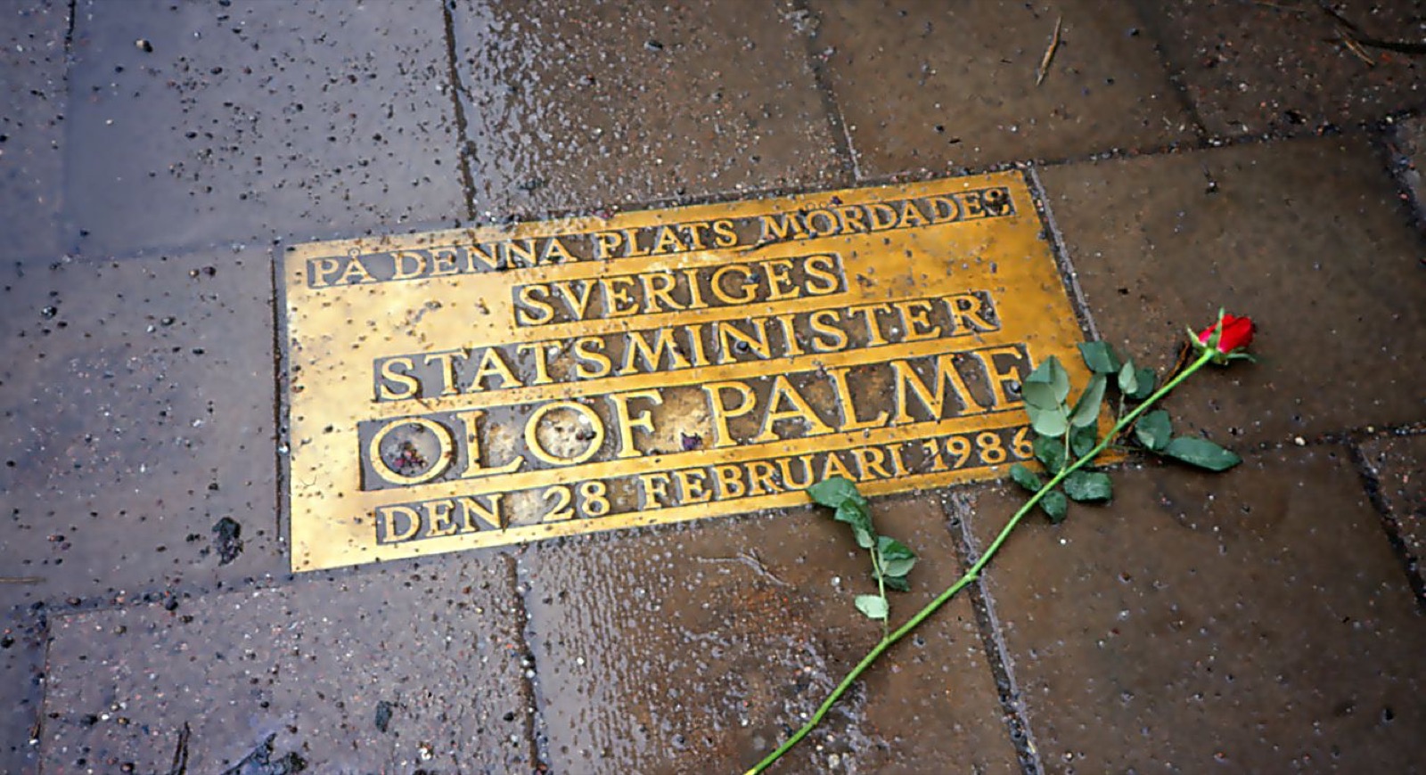 The Olof Palme memorial plaque set into the pavement on Sveavägen, Stockholm. Bronze, rectangular, reading 'Här mördades Sveriges statsminister Olof Palme den 28 februari 1986.'