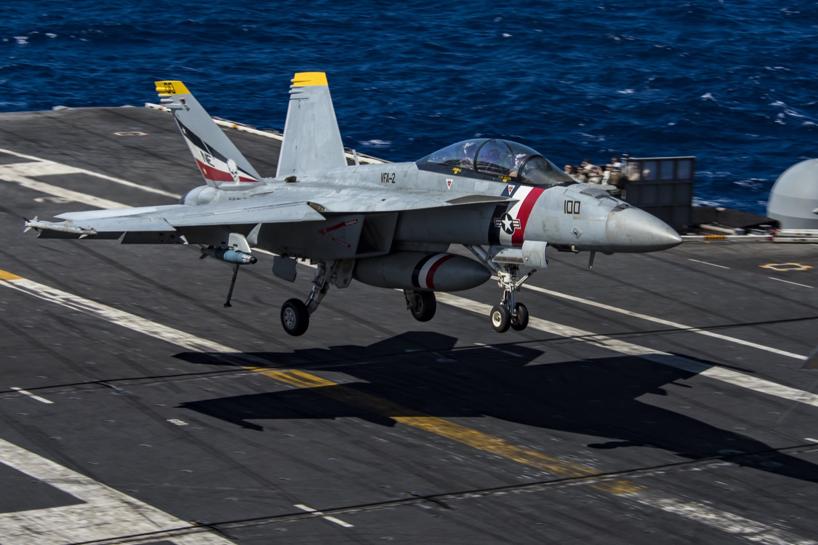 A U.S. Navy F/A-18F Super Hornet approaching a carrier landing — twin-engine, twin-seat, gull-grey paint, undercarriage extended, photographed against a daylight sky.