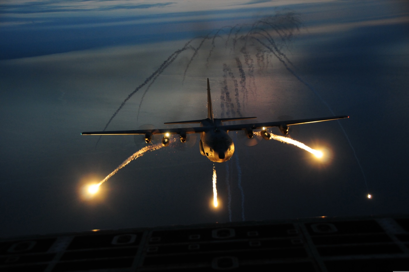 Military illumination flares descending at night, dropped by a military aircraft during a training exercise.