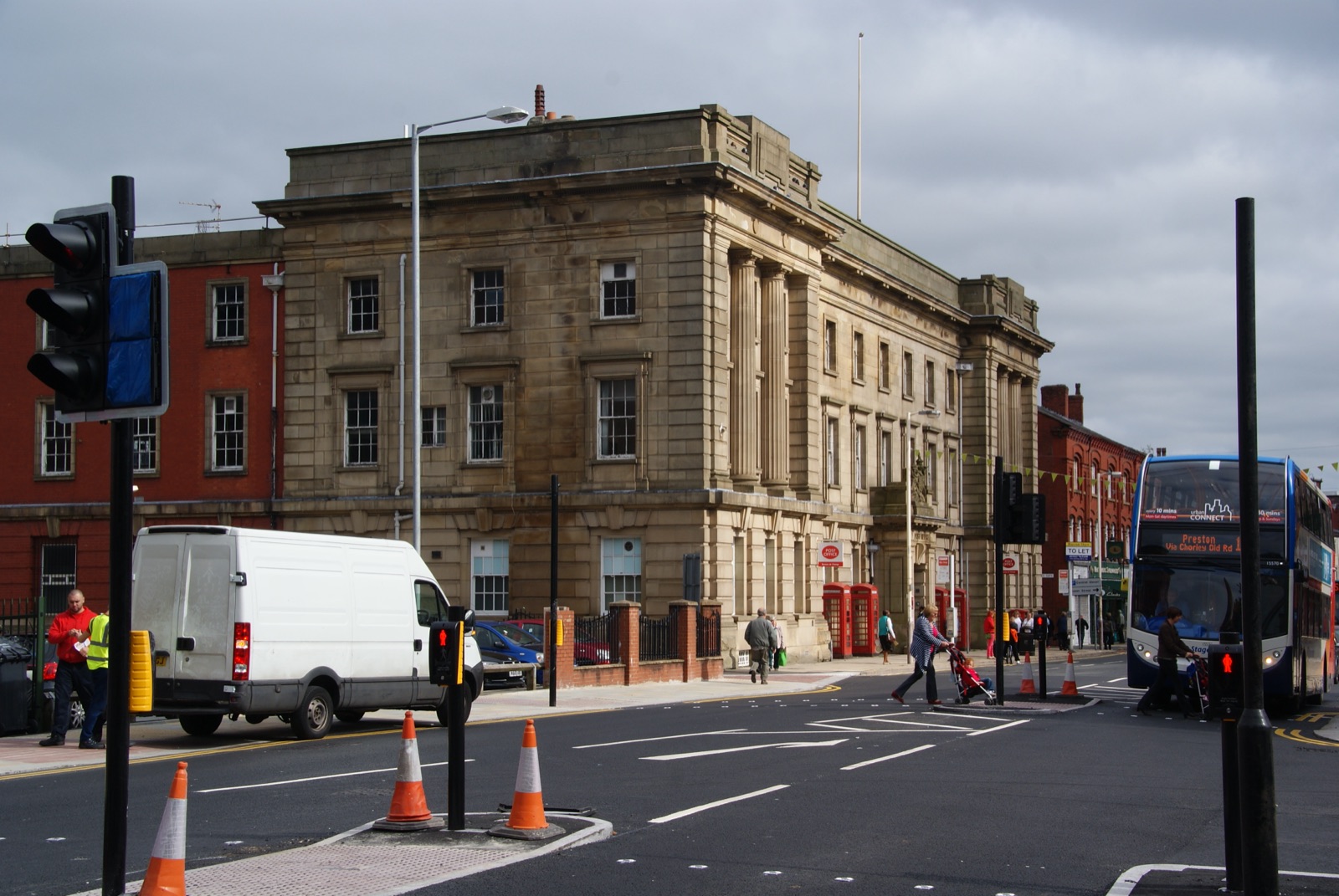 A Crown Post Office building in Bolton — a substantial early-twentieth-century stone civic building with arched ground-floor windows, a decorative parapet, and royal insignia, photographed from street level.