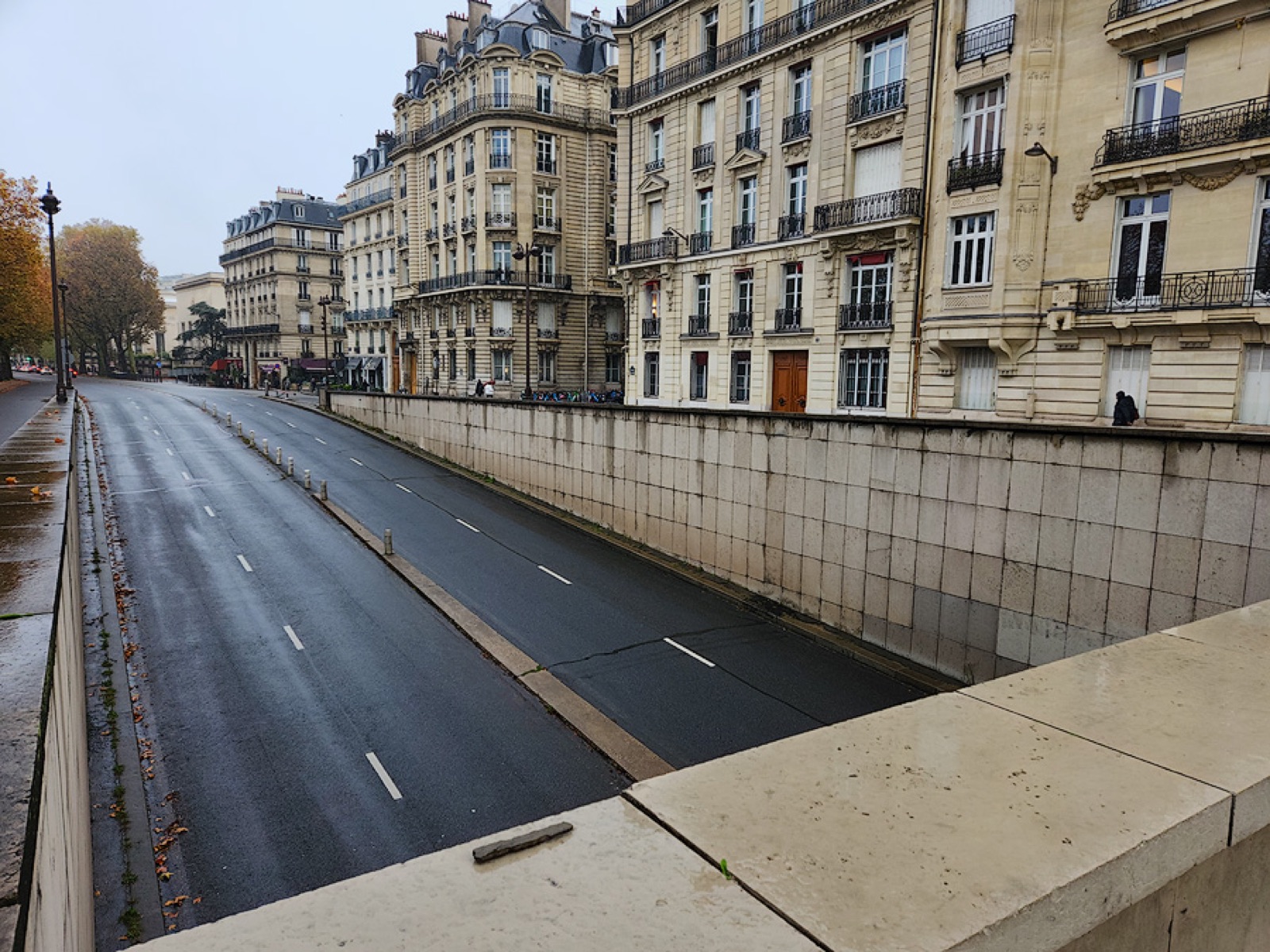 The west entrance of the Pont de l'Alma underpass in central Paris, photographed in daylight. The concrete tunnel curves slightly downward beneath the Place de l'Alma traffic circle.