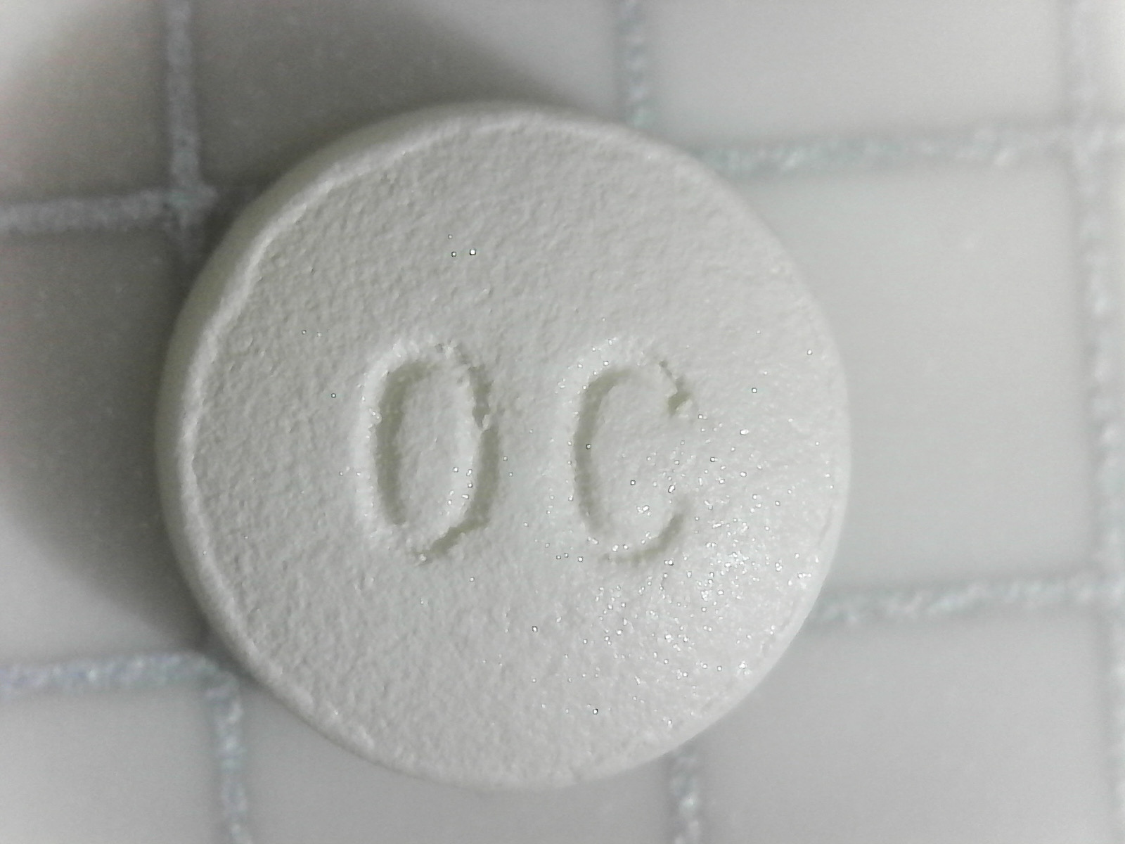 An OxyContin 10mg pill photographed in close-up, showing the 'OC' debossed on one side.