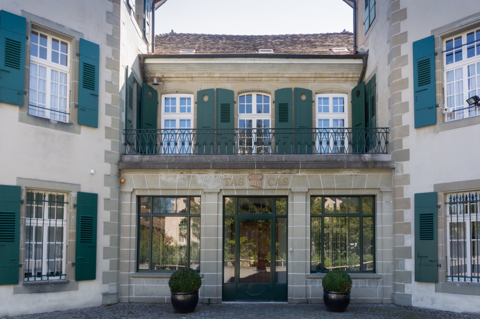 The exterior of the Court of Arbitration for Sport in Lausanne, Switzerland, a stately historic building with a steep roof and ornate façade set among trees.