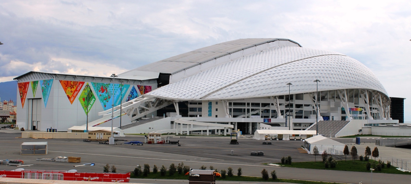 The Fisht Olympic Stadium in Sochi, a wide white domed stadium with a sweeping translucent roof, photographed against a blue sky.