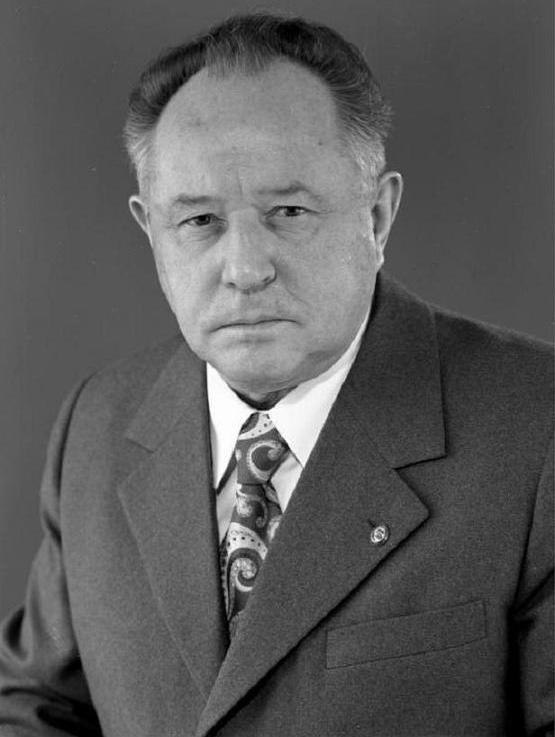 Erich Mielke in an official East German Bundesarchiv photograph — middle-aged man with thinning grey hair, wearing a dark double-breasted jacket and tie, photographed in formal portrait pose against a neutral background.