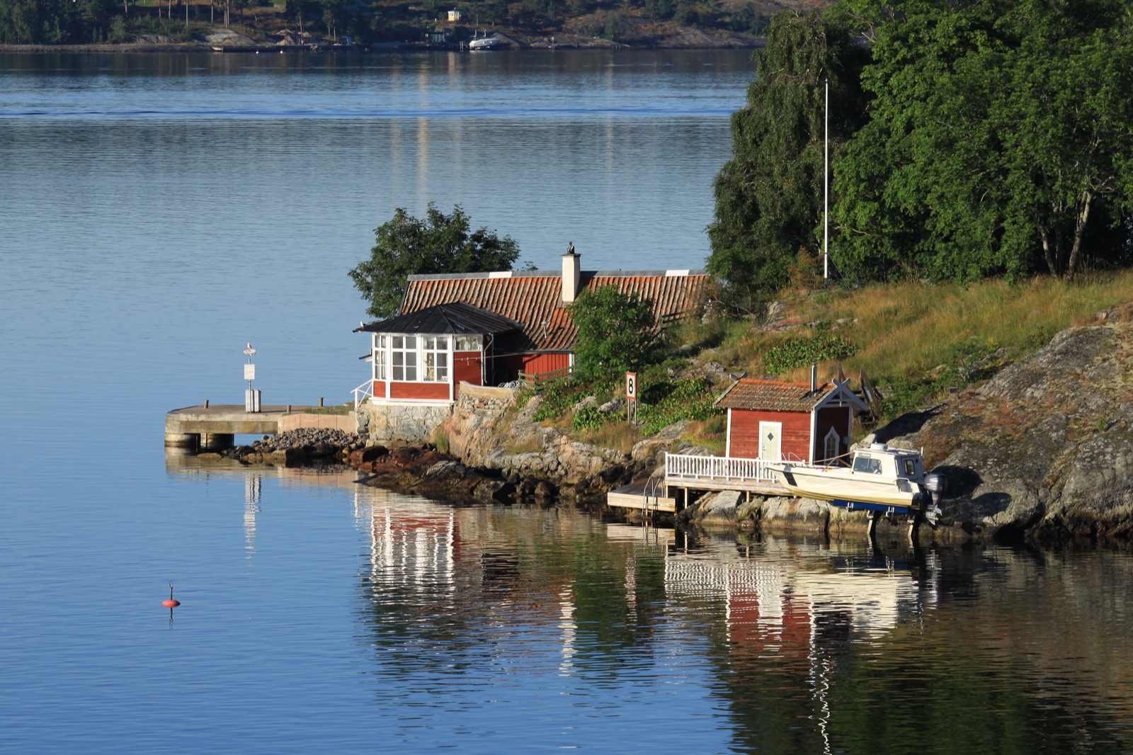 The Stockholm archipelago, a maze of forested rocky islands scattered across calm blue Baltic water under a clear sky.