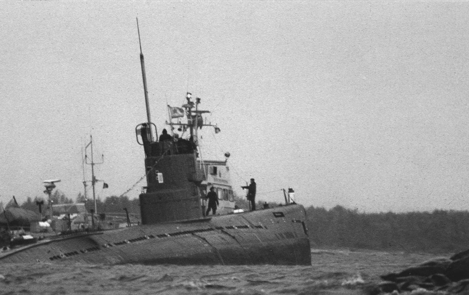A black-and-white photograph of the Soviet submarine U 137 run aground on rocks at Gåsefjärden near Karlskrona, Sweden, in 1981, crew members standing on its deck and conning tower.