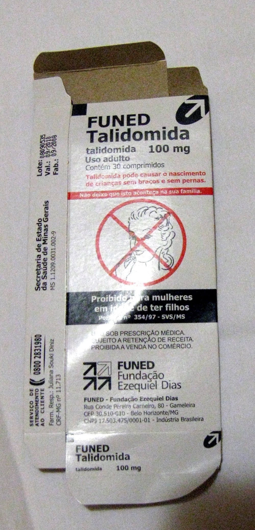 A modern Brazilian thalidomide medicine package labelled 'Talidomida 100 mg,' carrying a prominent warning symbol — a crossed-out drawing of a pregnant figure — and Portuguese text warning that it can cause birth defects and is prohibited for women of childbearing age.