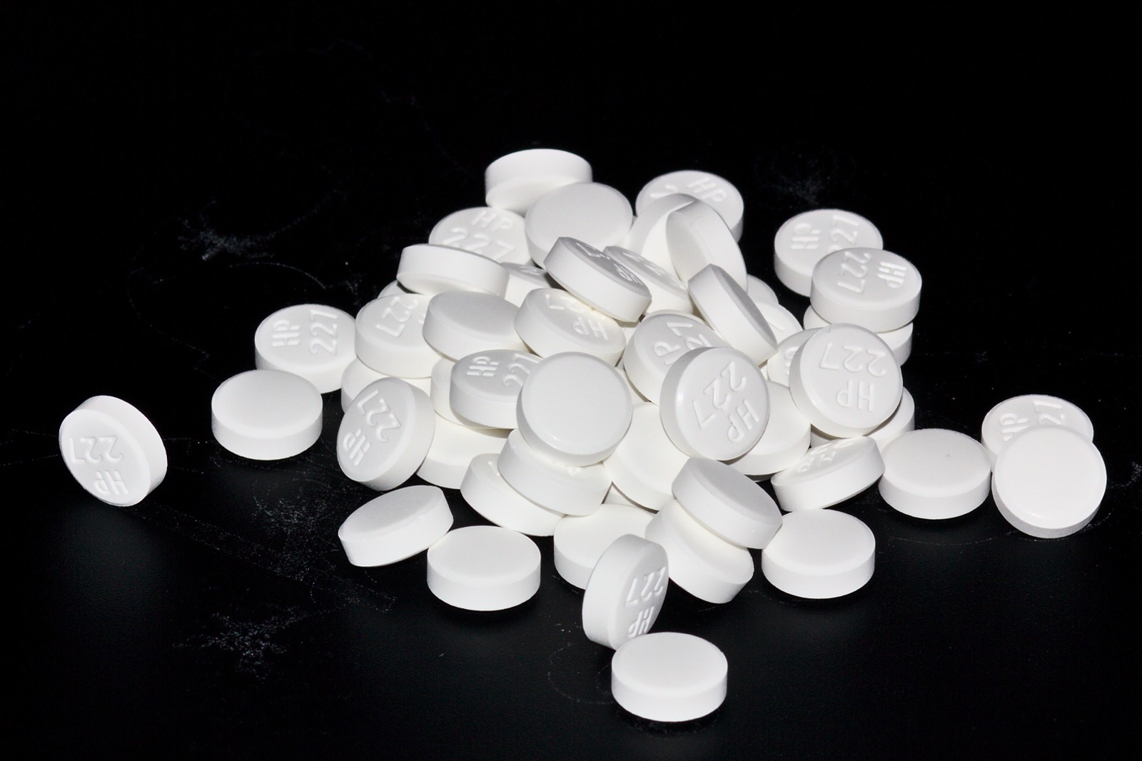 A close-up pile of plain round white tablets filling the frame.