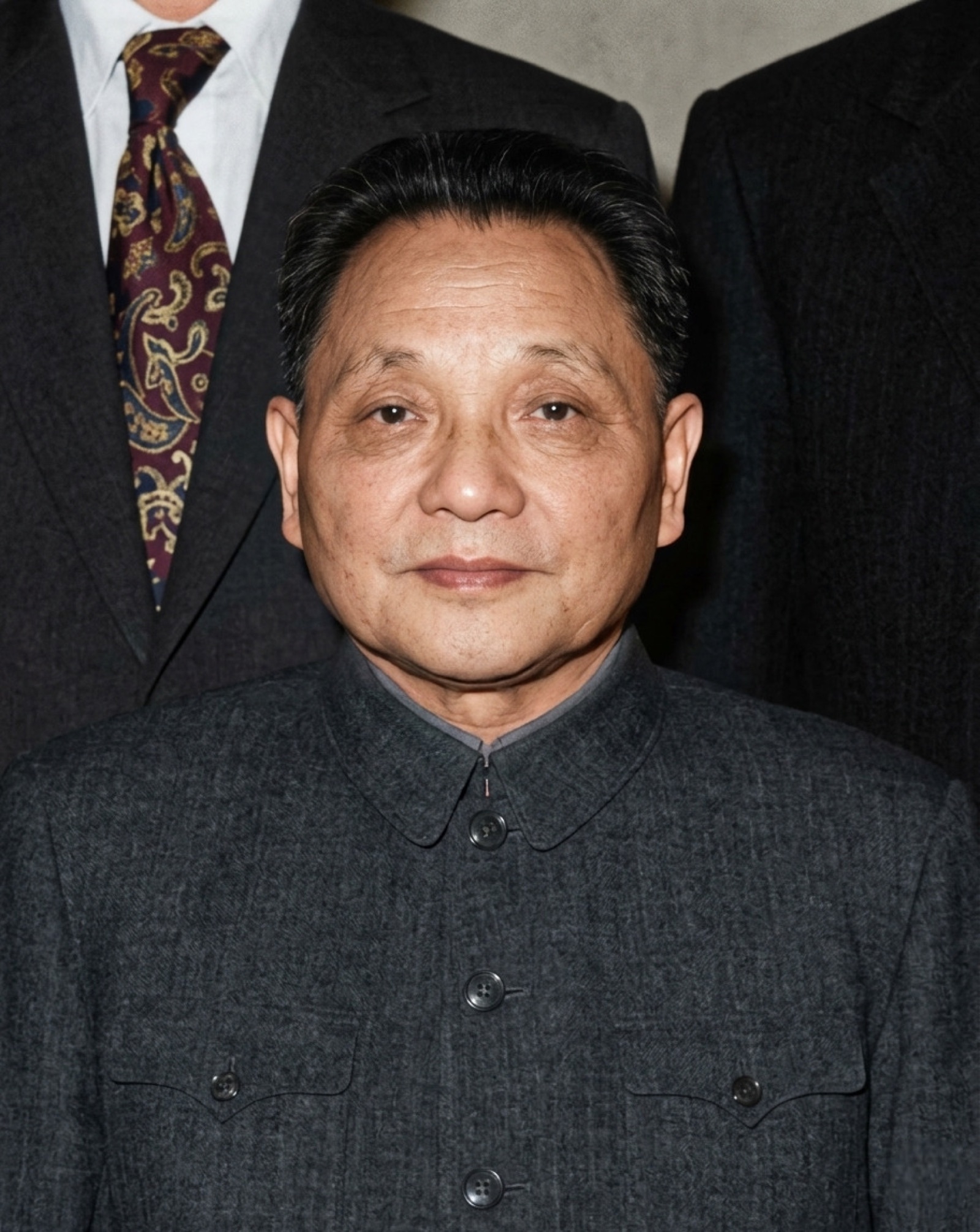 Deng Xiaoping photographed in a formal portrait — wearing a dark Mao suit, looking directly at camera.