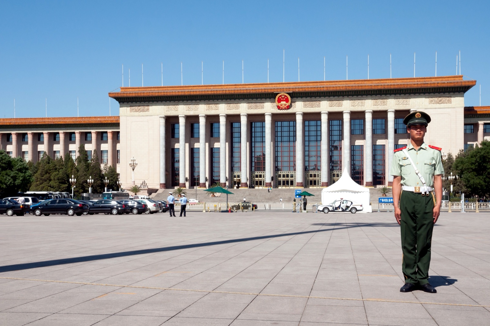 Tiananmen Square in Beijing, photographed in daylight — a vast paved plaza with the Monument to the People's Heroes at center and the Great Hall of the People along one side.