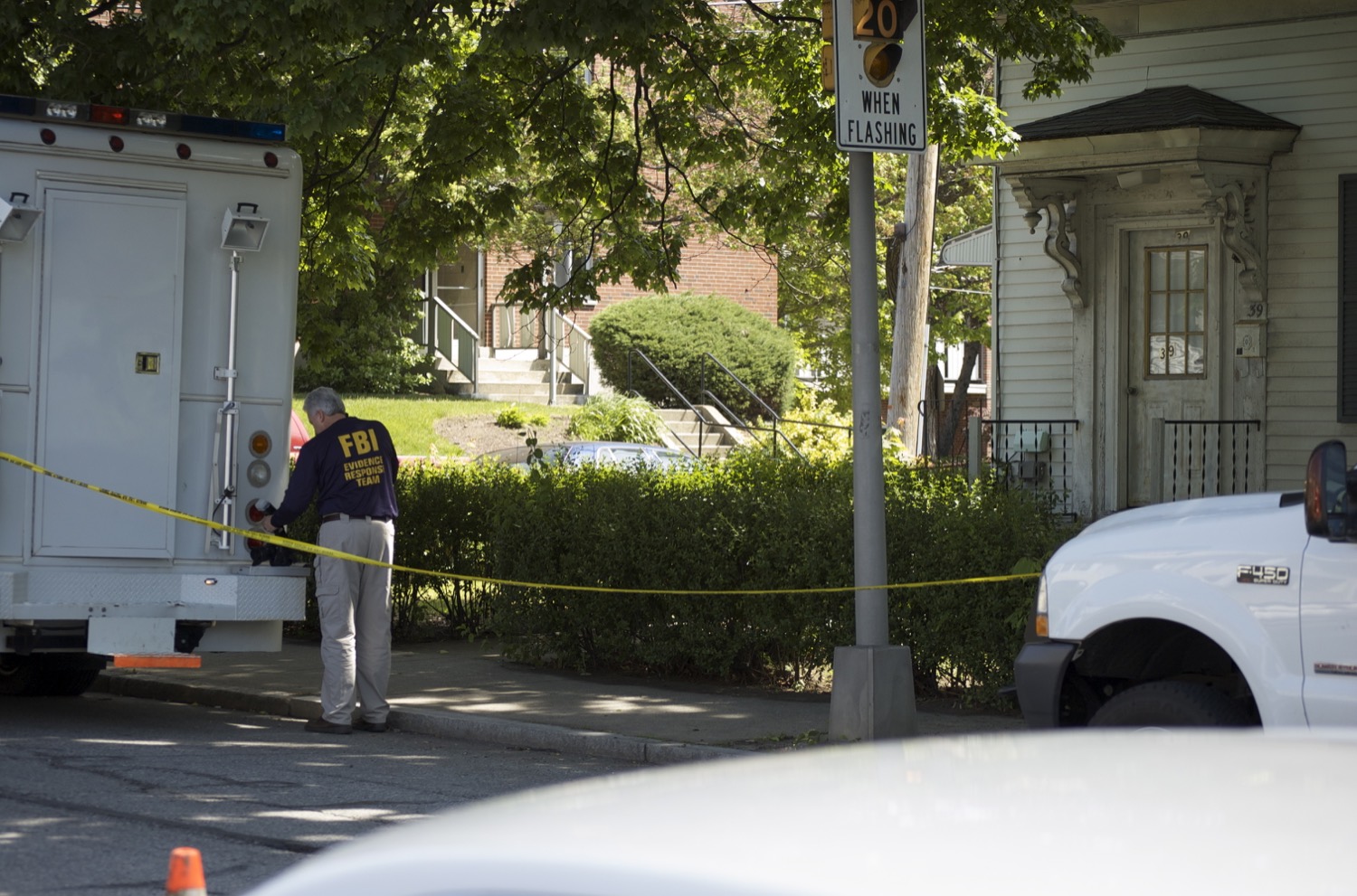 FBI agents and vehicles during a federal raid, agents in tactical gear near official trucks.