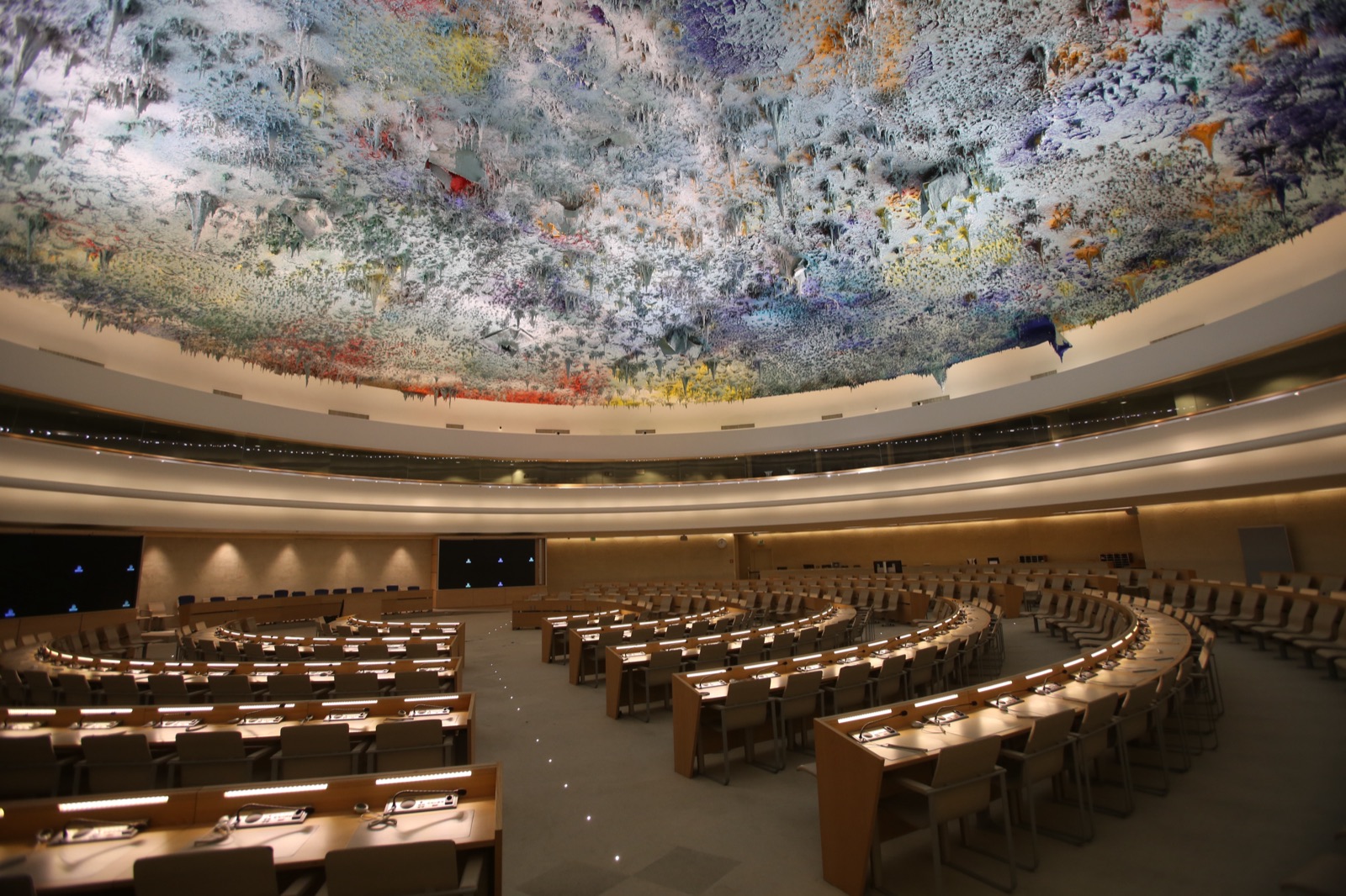 The Human Rights and Alliance of Civilizations Room at the United Nations in Geneva, a large chamber with rows of desks beneath a famous multicoloured stalactite ceiling sculpture.