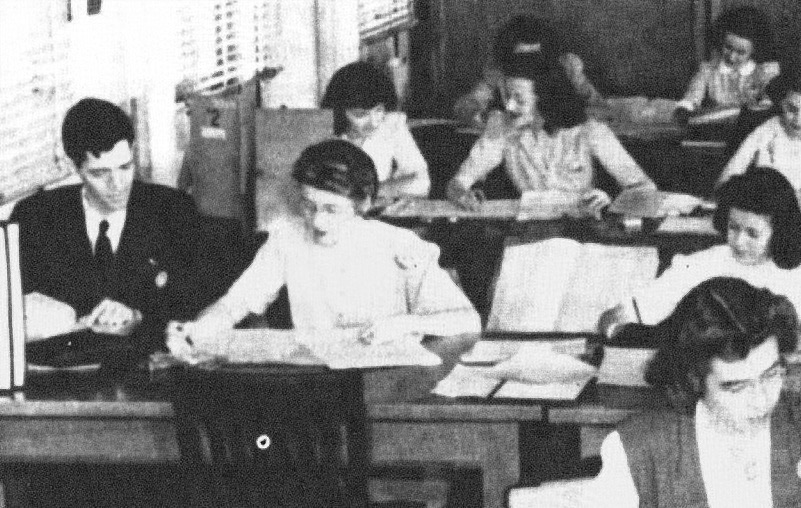 Meredith Gardner, at far left, working with fellow cryptanalysts at a table covered with papers.