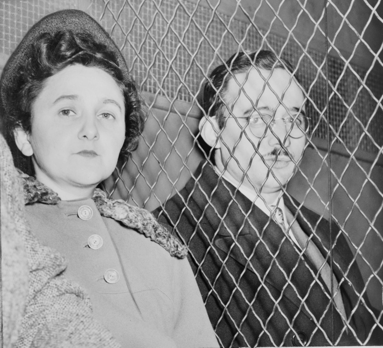Julius and Ethel Rosenberg behind a wire screen, photographed after their arrest.