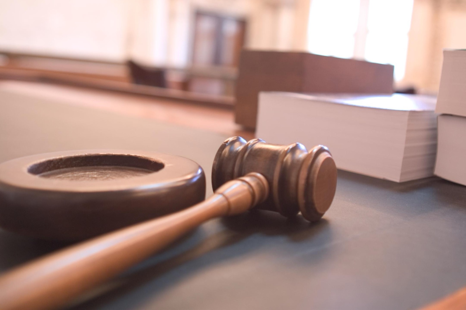 A wooden judge's gavel resting on its sound block on a desk in a courtroom.