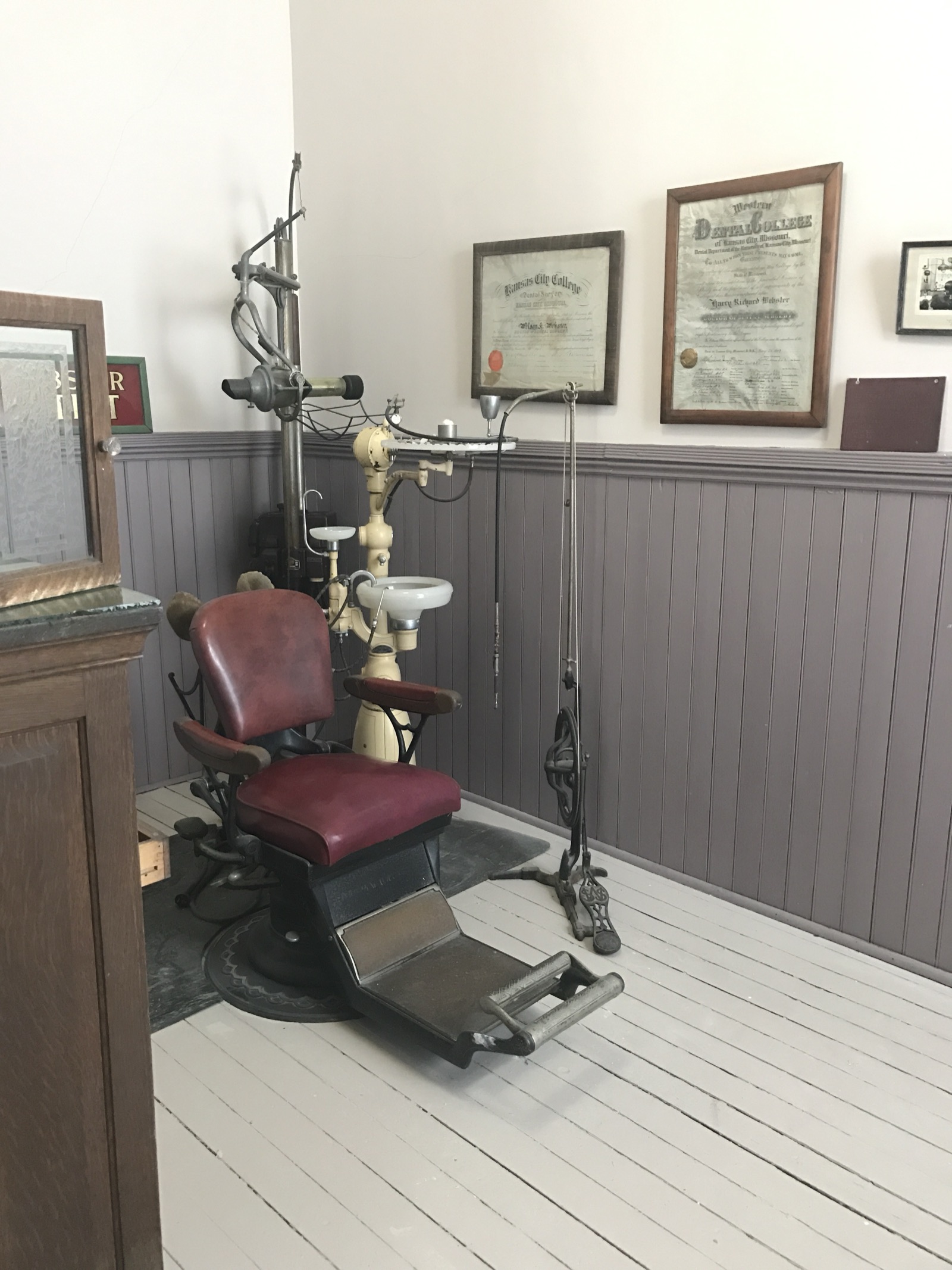 A recreation of a historic dental surgery, with an antique dentist's chair, foot-powered drill, and period cabinets and instruments.