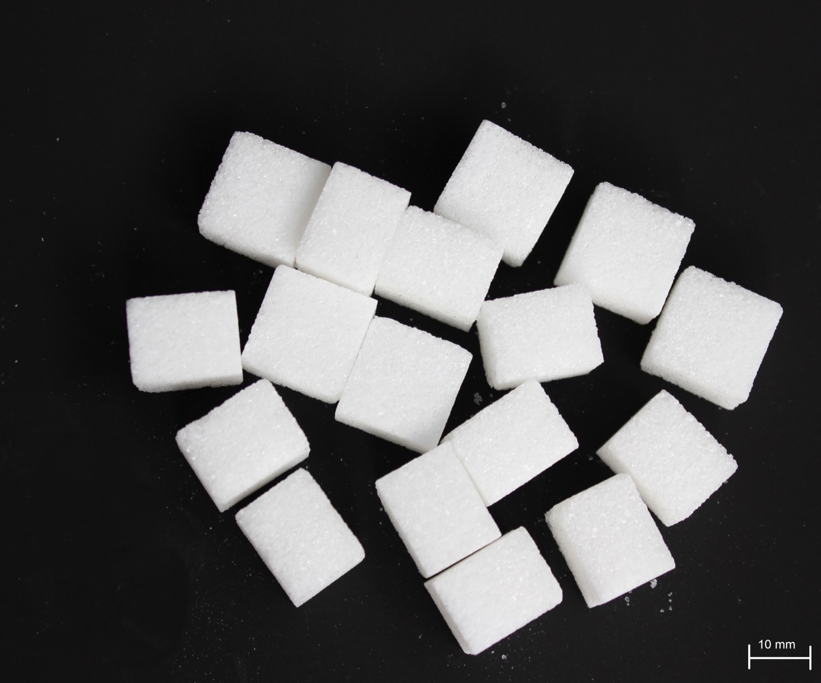A close-up pile of white sugar cubes, neatly stacked, filling the frame.