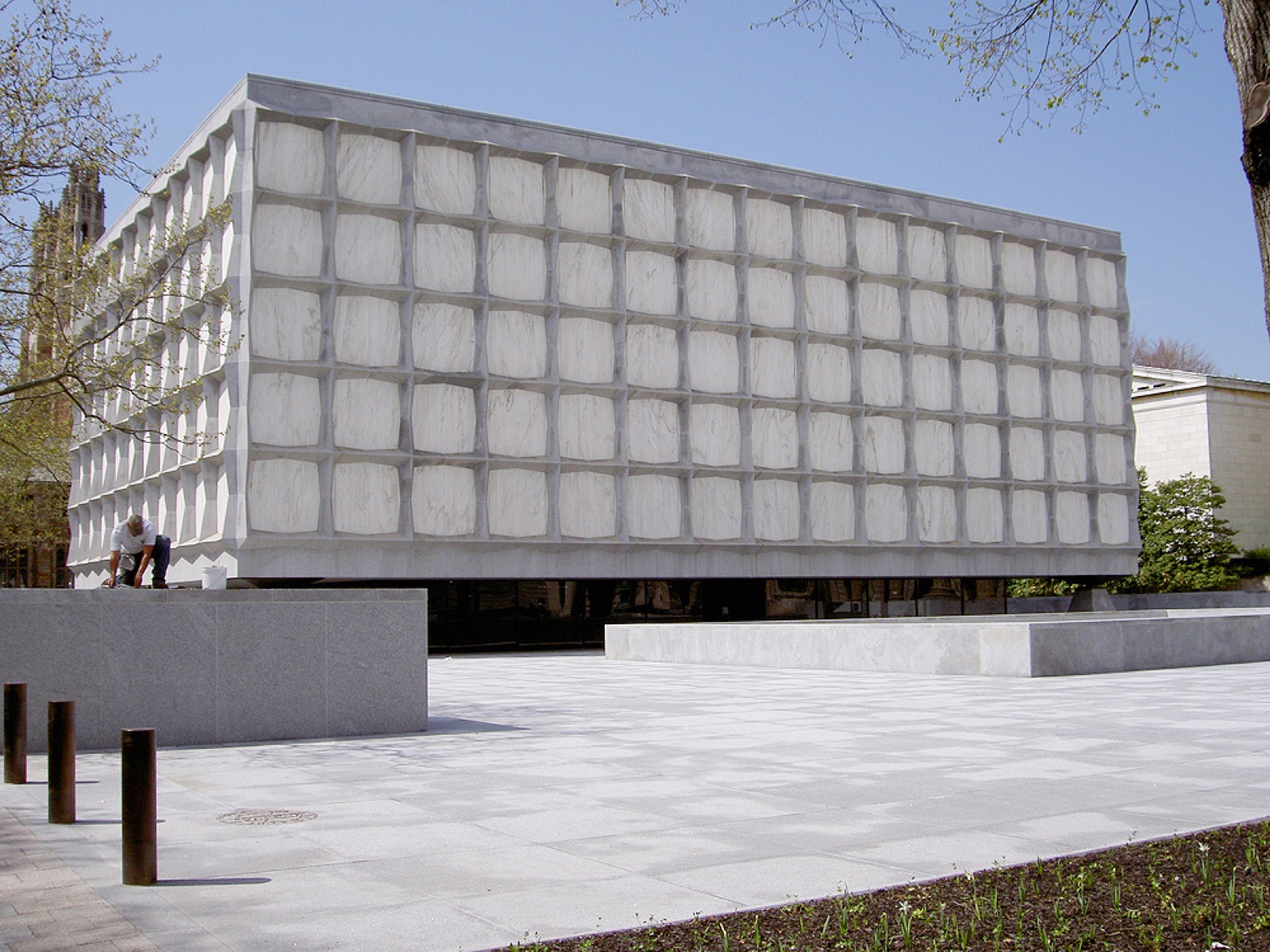 The Beinecke Rare Book and Manuscript Library at Yale University — a modernist 1963 building of translucent Vermont marble panels held in a grey-granite grid frame, photographed from the plaza at street level.