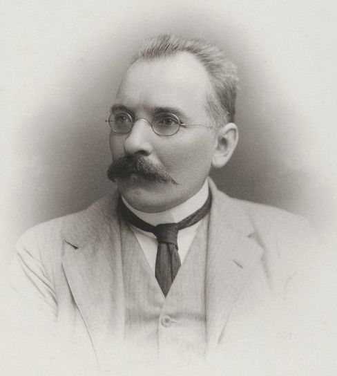Wilfrid Voynich, photographed circa 1920 — middle-aged man with a dark mustache, three-piece suit, formal portrait pose.