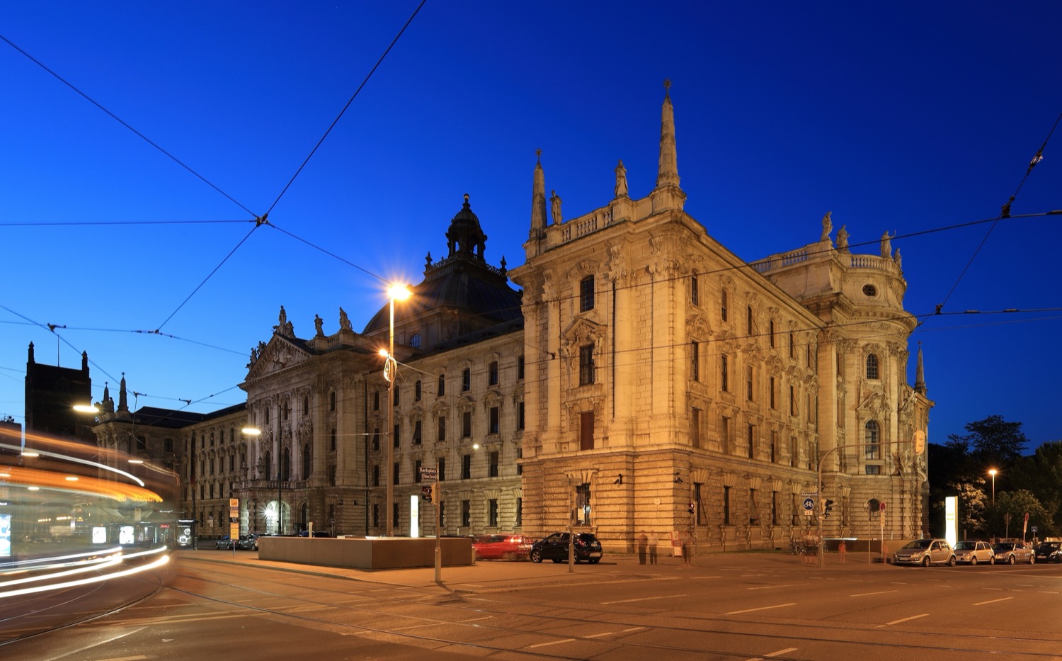 The Palace of Justice (Justizpalast) in Munich, Germany, a grand domed building illuminated at dusk.
