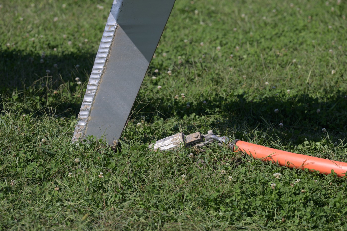 Workers laying fiber-optic telecommunications cable, with spools of cable and conduit at a worksite.